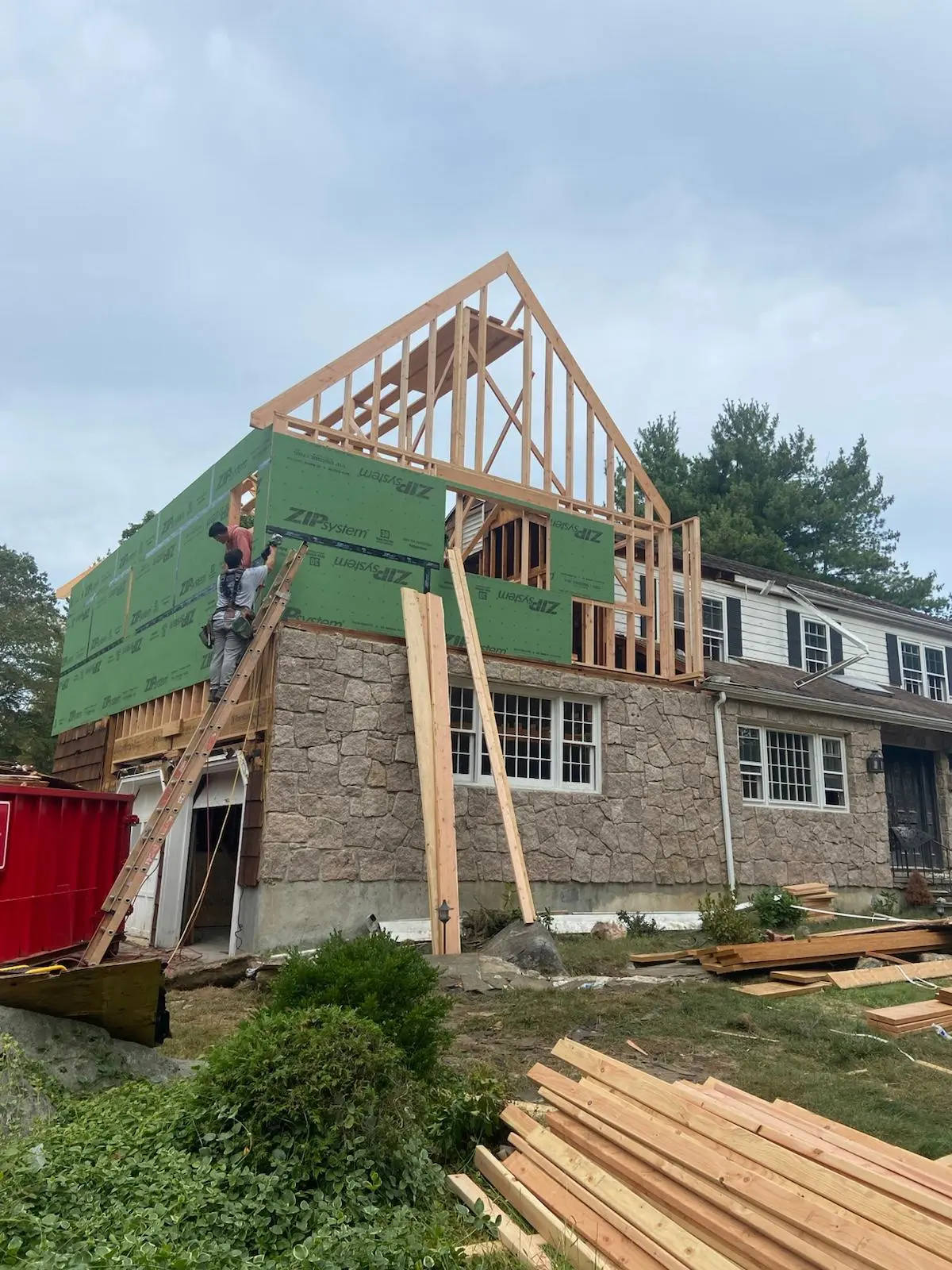Addition over a brick home with green sheathing, built by Mosquera Construction in Connecticut