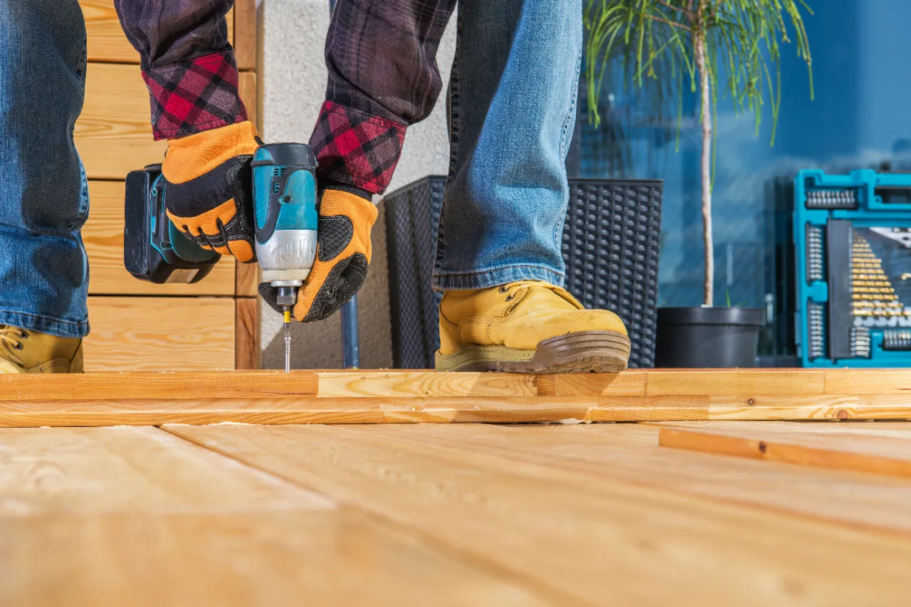 Carpenter fastening wood deck boards with a drill