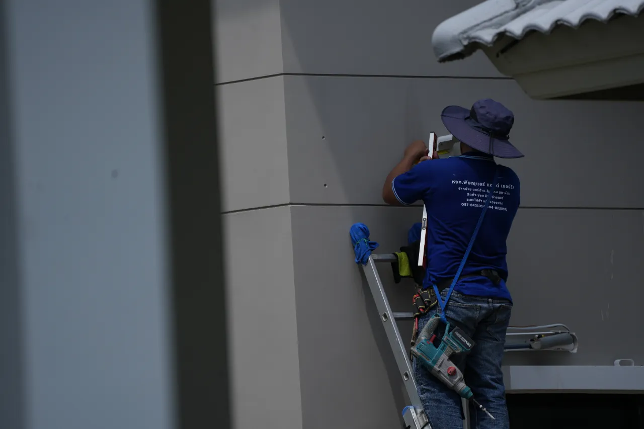 Technician working on a gray exterior wall