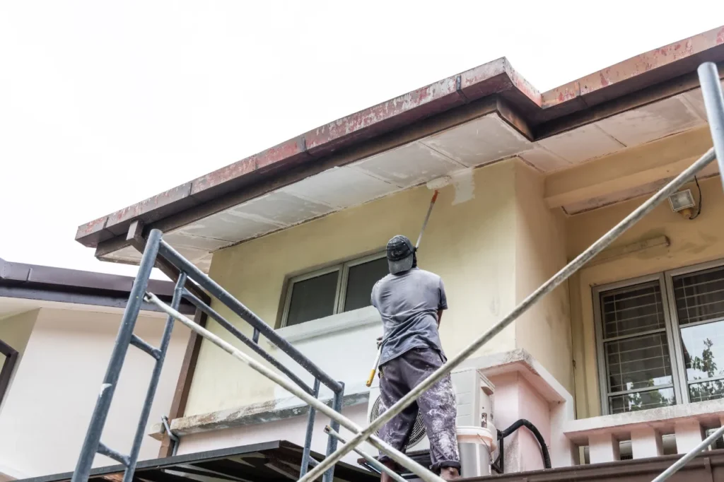 Painter applying fresh paint to a home exterior