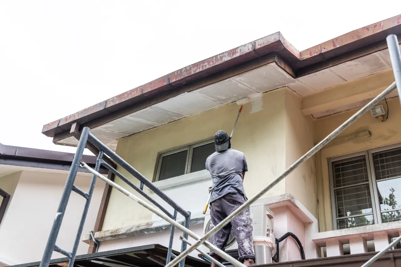 Painter applying fresh paint to a home exterior